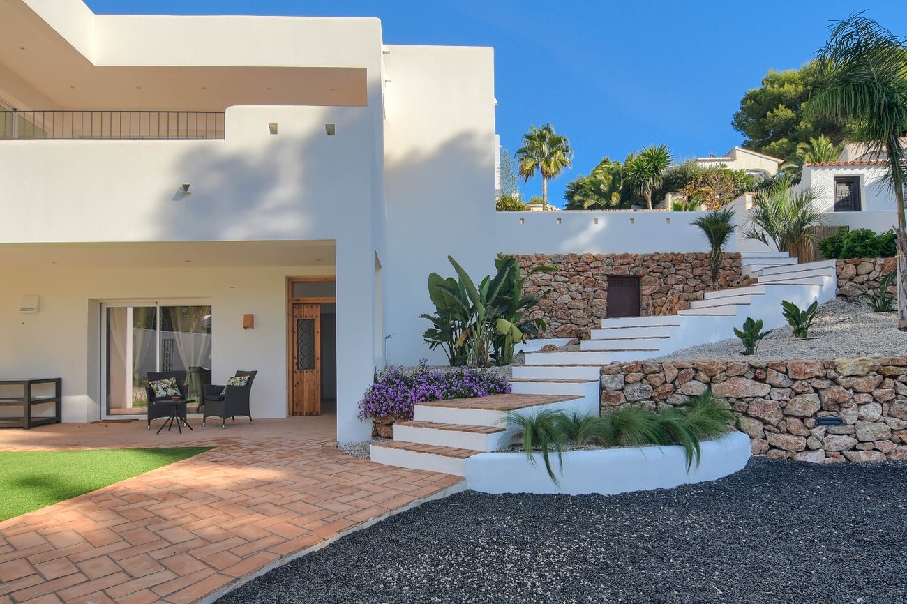 Casa Eucaliptus — terraza cubierta junto a la entrada con escalera hacia el jardín superior
