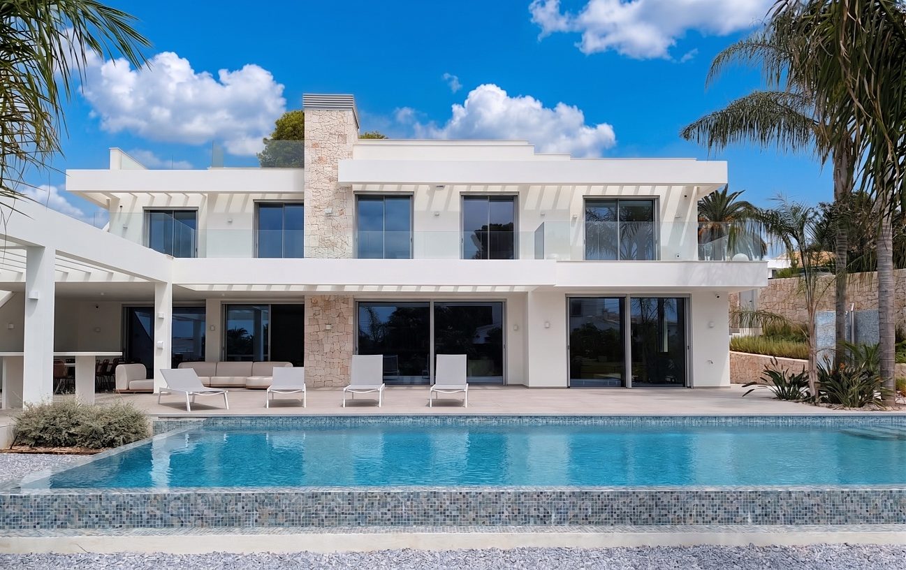 Villa Mar de Japón — fachada posterior con la piscina desbordante, la pérgola y el elemento de chimenea en piedra natural