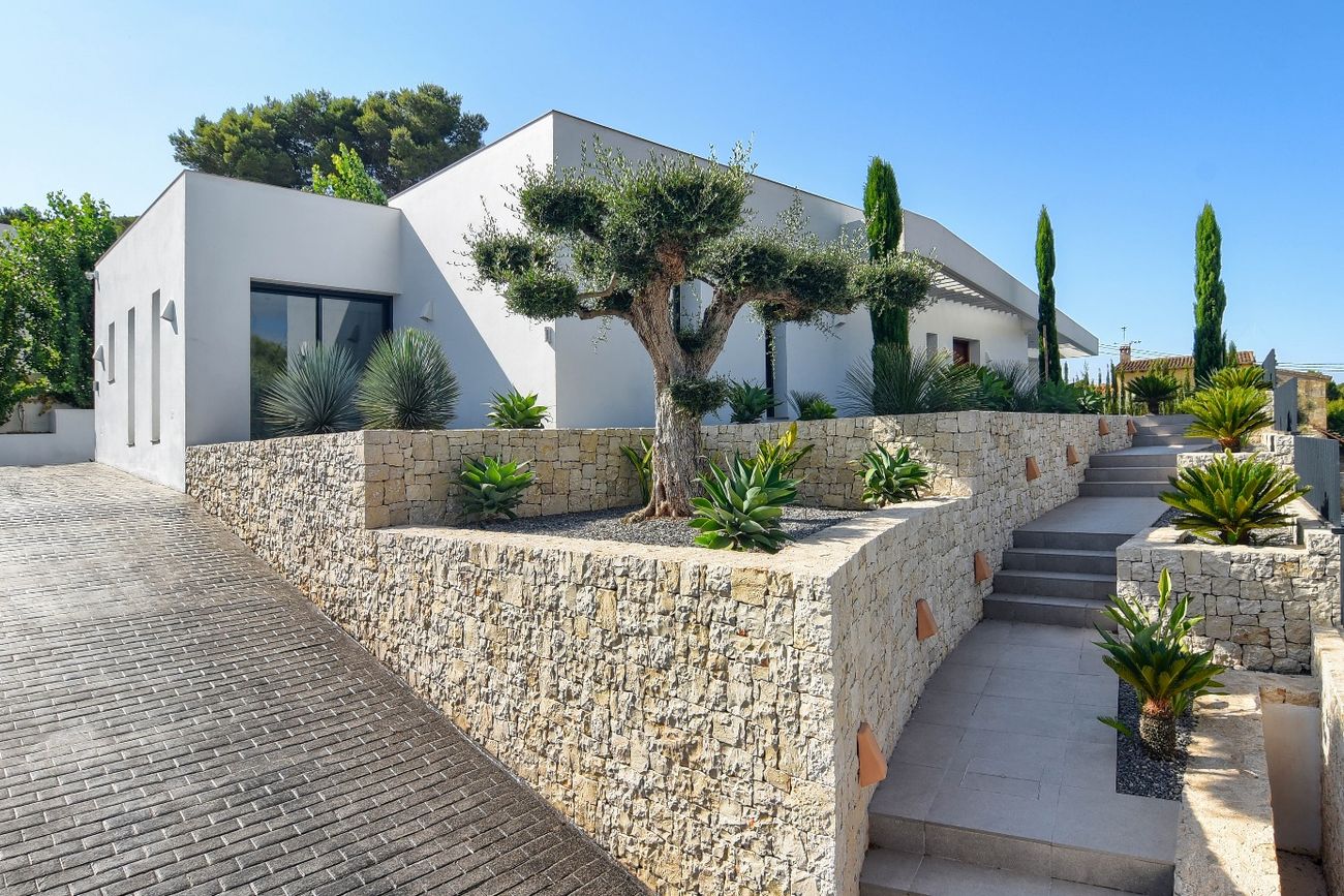 Casa Pintor Gris — fachada con olivo y muros de piedra natural